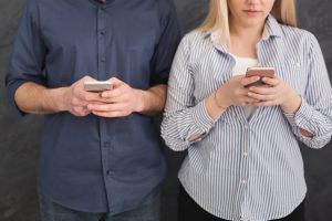 young-unrecognizable-couple-ignoring-each-other-with-phones-992864502_2125x1416