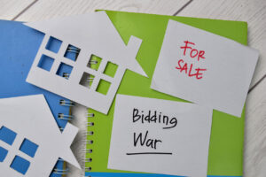 Bidding War and House For Sale write on sticky notes isolated on Office Desk